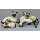 Five Siamese cat figures including Beswick and Royal Doulton
