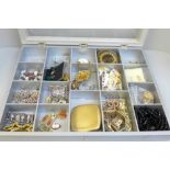 A display case with costume jewellery, compacts and a pocket watch