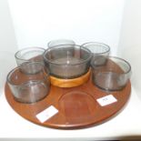 A teak lazy Susan with glass dishes, one lacking