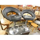 A pair of chrome and black vinyl revolving bar stools