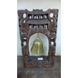 A oriental brass bell, on carved wood stand