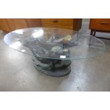 An oval glass topped coffee table, on faux bronze dolphin base