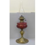 A Victorian or Edwardian Hinks oil lamp with cranberry glass reservoir, on a brass Art Nouveau base