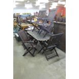 A teak garden table and six folding chairs