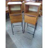 A pair of teak cabinets on black metal stands