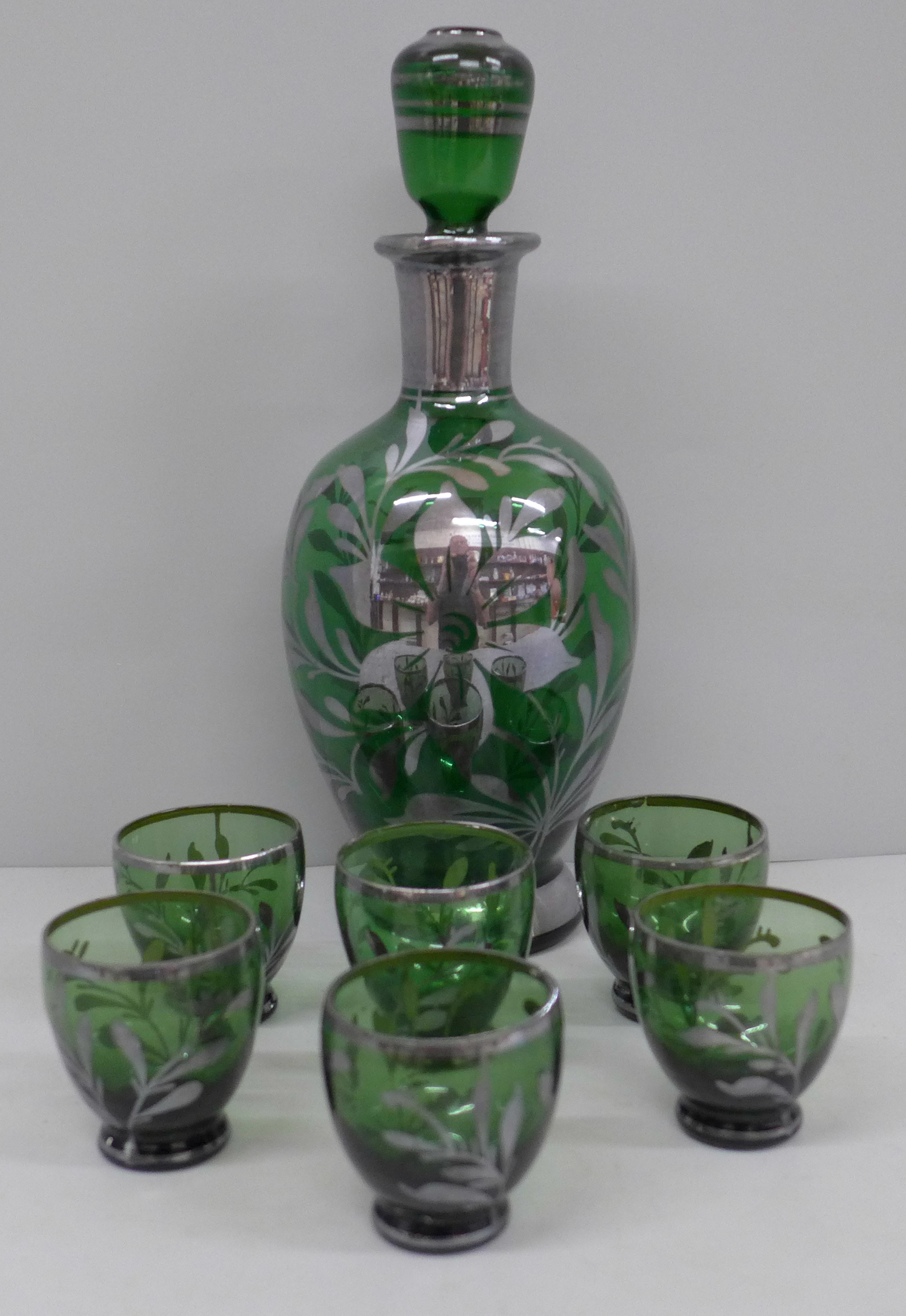 A liqueur set; silver overlay green glass decanter and six glasses