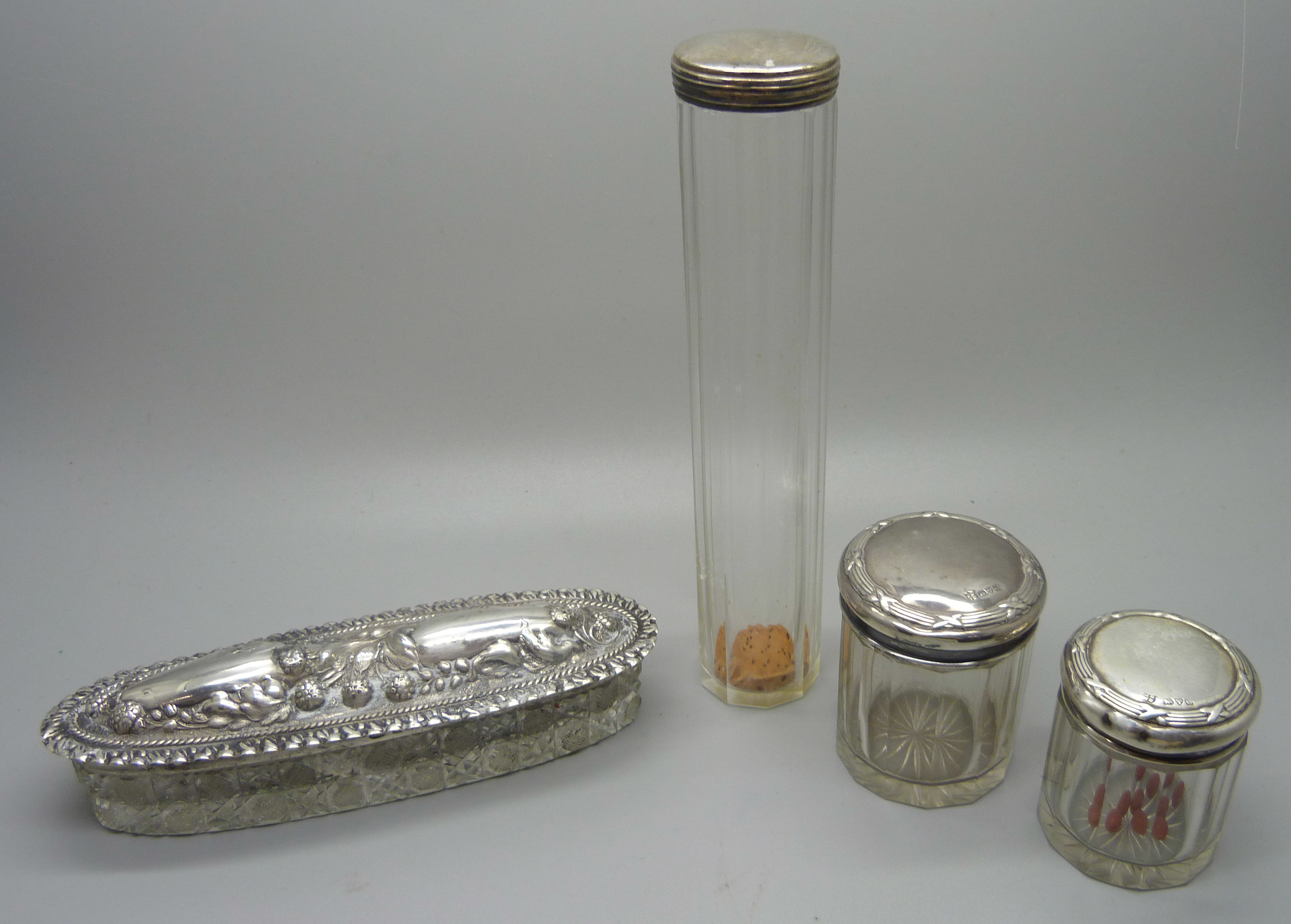 Three silver topped glass jars and a silver topped glass bottle