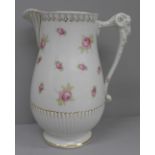 A jug decorated with hand painted roses and a ram's head handle, with raised 'Adam' mark to base,