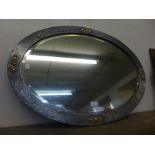 An Arts and Crafts pewter and brass oval framed mirror