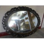 An Edward VII carved oak oval framed mirror