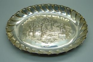 An oval silver tray with embossed scene of an outside tavern, ladies dancing to a piper with