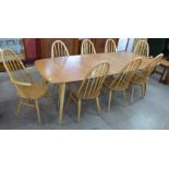 An Ercol Blonde elm and beech Grand Windsor extending dining table and eight Ercol Blonde Quaker