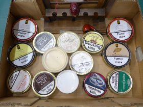 A collection of fourteen tins of pipe tobacco, a rack and two pipes