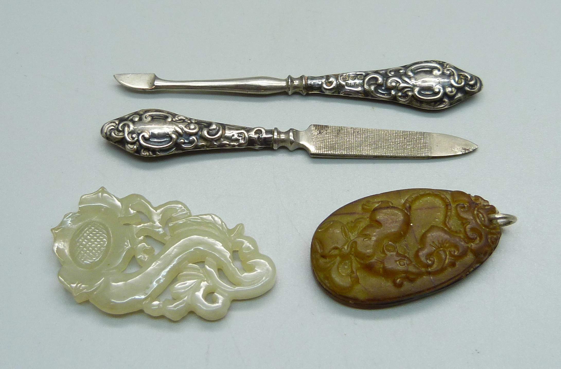 A carved jade pendant, one other pendant and two silver mounted manicure tools