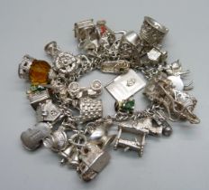 A silver bracelet with over 30 silver and white metal charms, 132g