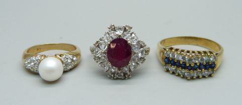 A silver ring with red stone, N, and two costume rings
