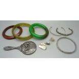 Two jade bangles, a wooden bangle, a white metal mirror, three bangles and a pendant and chain