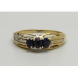 A silver gilt and three sapphire ring with two small diamond accents on the shoulders, X