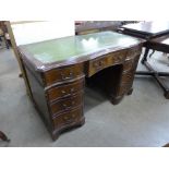 A mahogany and green leather topped serpentine pedestal desk