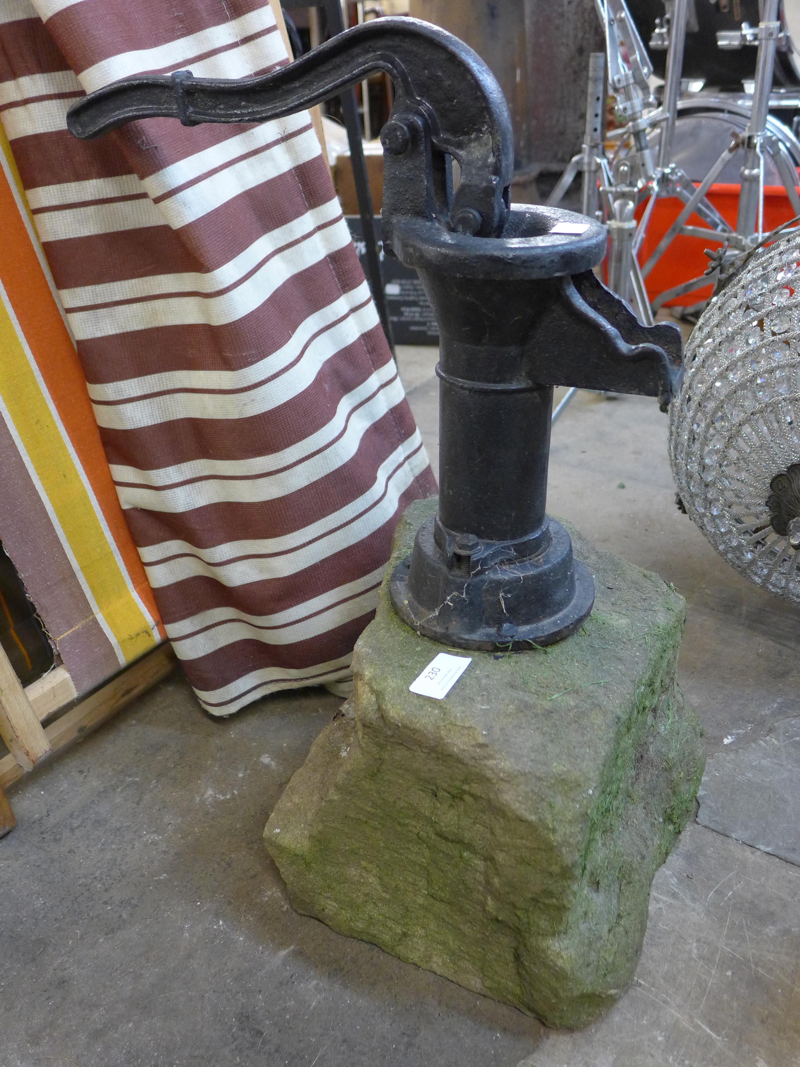 A cast iron water pump, mounted on a stone block