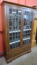 An Arts and Crafts oak and stained glass two door bookcase