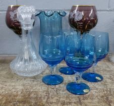 A collection of glassware including a decanter, four blue glasses, a blue vase and two taller