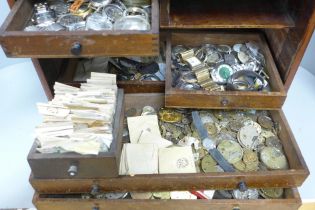 A collection of watch parts, movements, cases, glasses, etc., in an engineers chest