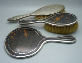 A silver mounted tortoiseshell mirror, Birmingham 1919, and two brushes