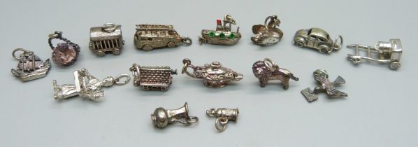 A collection of fifteen silver and white metal charms including fire engine, VW Beetle, lion, boat