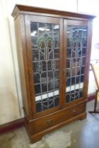 An Arts and Crafts oak and stained glass two door bookcase