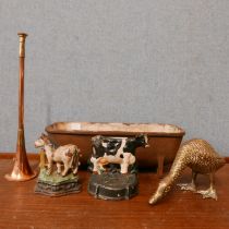 A small cast iron feeder, two cast iron door cow shaped stops, brass duck and a small copper horn