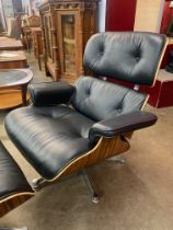 A Charles & Ray Eames style simulated rosewood and black leather revolving lounge chair and ottoman