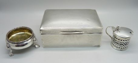 A silver cigarette box with engine turned detail, a silver salt cellar and condiment with blue glass