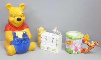 A Winnie The Pooh money box, perpetual calendar and novelty mug
