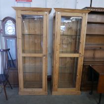 A pair of tall pine single door display cabinets