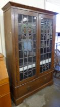 An Arts and Crafts oak and stained glass two door bookcase