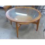 A circular teak and glass topped coffee table