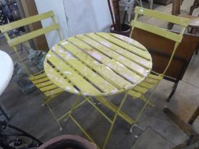 A circular painted folding garden table and two chairs