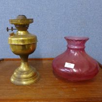 A brass oil lamp, with cranberry glass shade