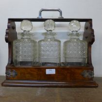 An early 20th Century oak tantalus, with three glass decanters
