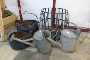 Two cast iron cauldrons, a wrought iron planter and two galvanised watering cans