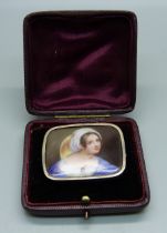 A hand painted porcelain brooch, set in white metal, lacking pin, cased, 41mm wide