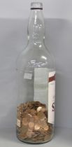 A 4.5 litre Bell's Finest Old Scotch Whisky bottle, approximately 30% full with copper 1p and 2p