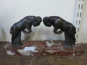 A pair of spelter ram bookends, on rouge marble socles