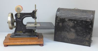 An early child's sewing machine in tin holder, in working order