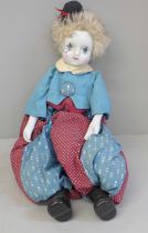 A vintage clown doll with porcelain head and arms