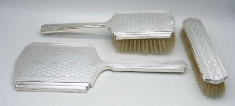 A three piece silver vanity set, hand mirror and two hair brushes, Birmingham 1951