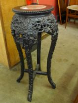 A late 19th/early 20th Century carved hardwood and marble topped jardiniere stand