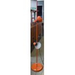 An orange metal floor standing spotlight lamp