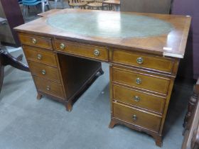 A George III style inlaid yew wood and green leather topped pedestal desk